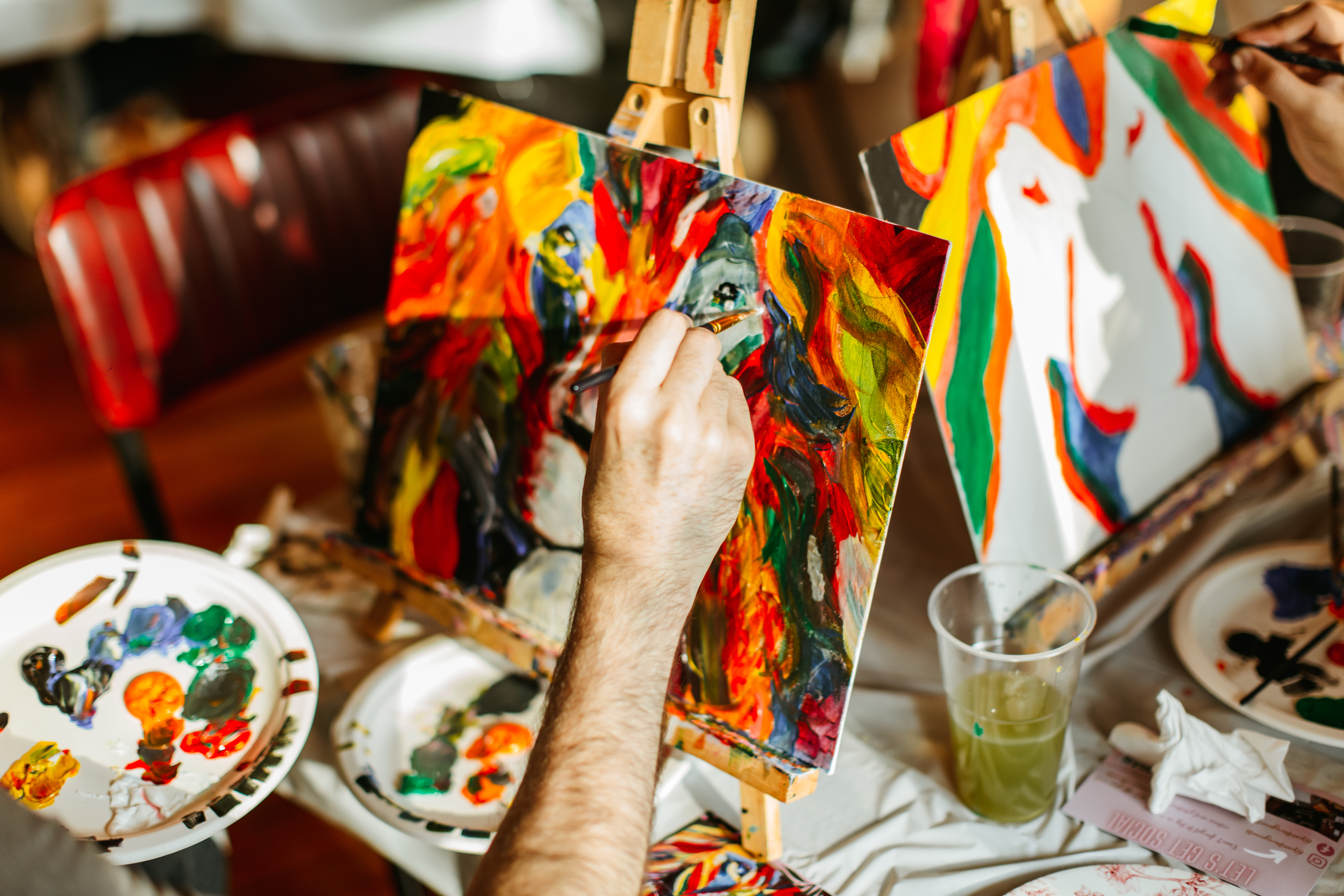 Hand holding a brush painting a small canvas